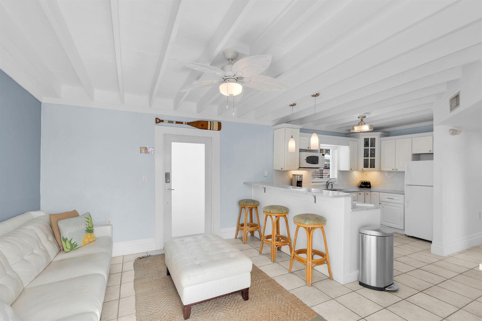 A living room and kitchen area with a white sofa, breakfast bar, and tiled floors — 11725 3rd Avenue Ocean, Marathon FL 33050, MARATHON, FL