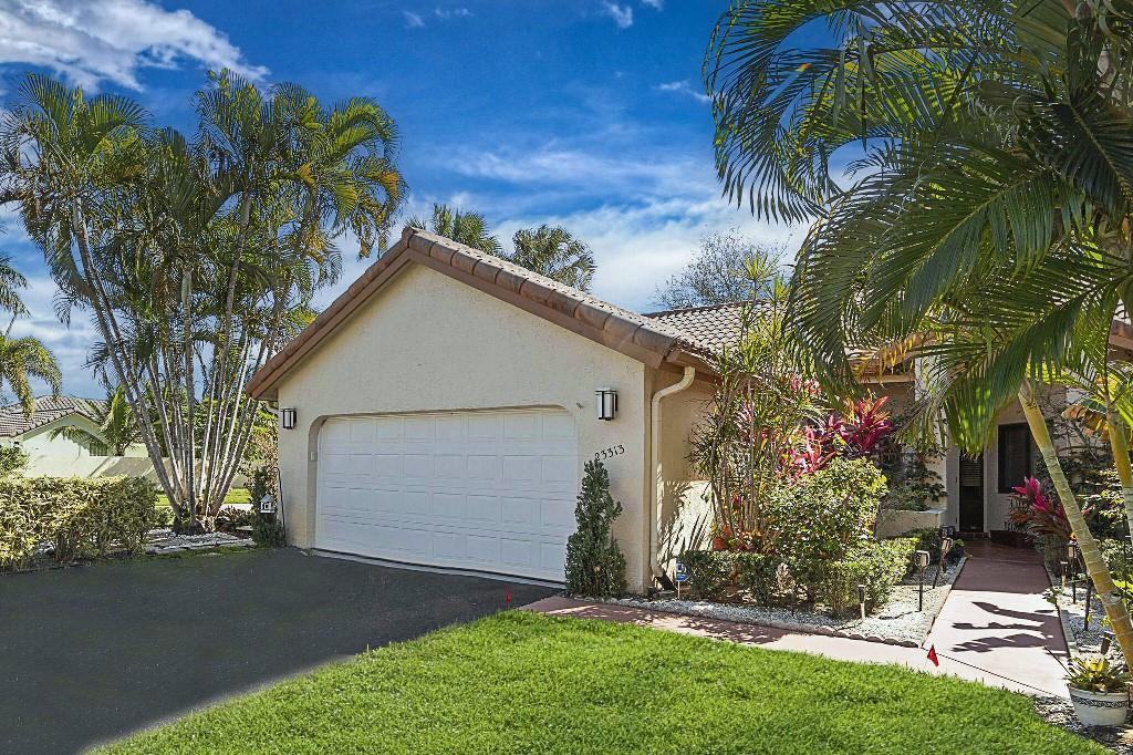 A single-story house with a white garage door, tan stucco walls, and tropical landscaping — 23313 Water Circle, Boca Raton FL 33486, BOCA RATON, FL