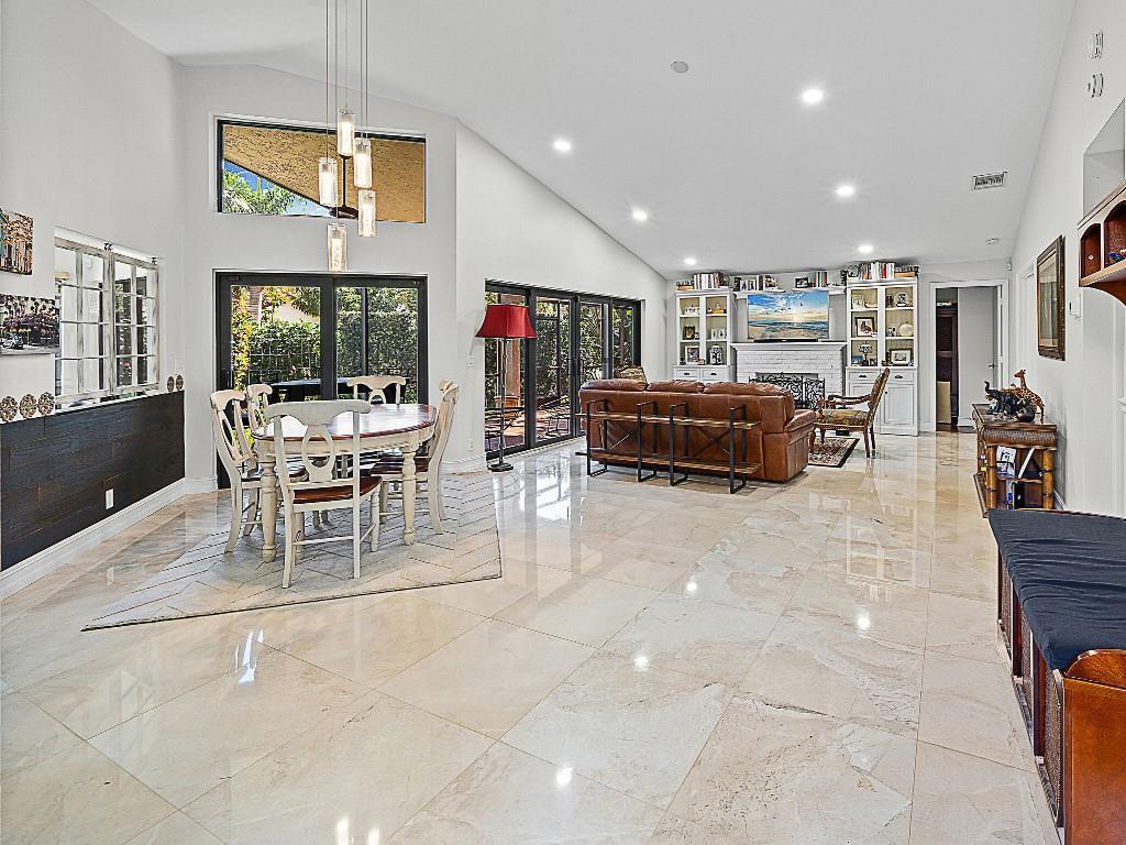 An open-concept living and dining area features vaulted ceilings, tile flooring, and large sliding glass doors — 23313 Water Circle, Boca Raton FL 33486, BOCA RATON, FL