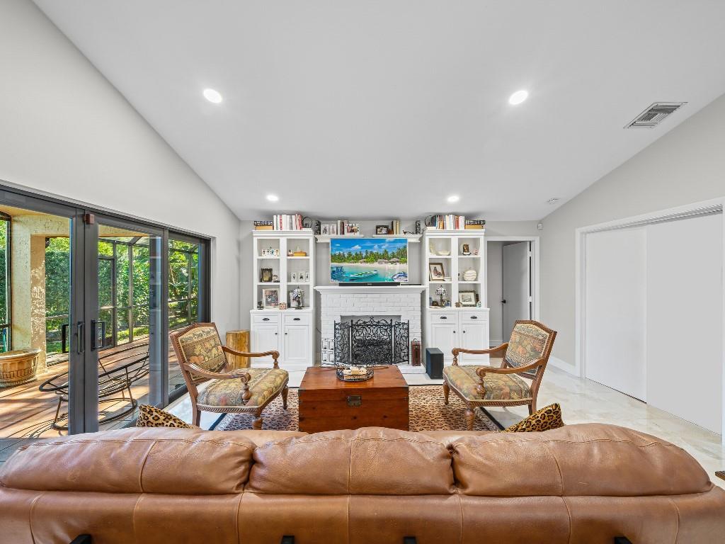 A living room features a white fireplace, built-in shelving, two patterned chairs, and a leather sofa — 23313 Water Circle, Boca Raton FL 33486, BOCA RATON, FL