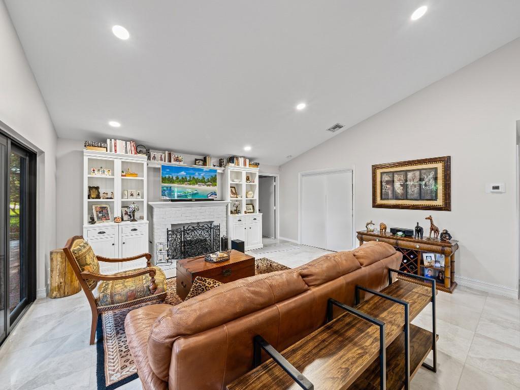 A living room features a white fireplace, built-in shelving, a leather sofa, and tile flooring — 23313 Water Circle, Boca Raton FL 33486, BOCA RATON, FL