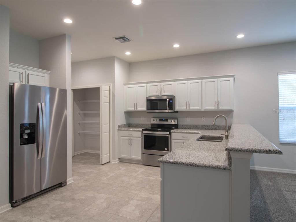 A kitchen with white cabinets, stainless steel appliances, granite countertops, and a walk-in pantry — 1097 GRANTHAM DRIVE, SARASOTA, FL