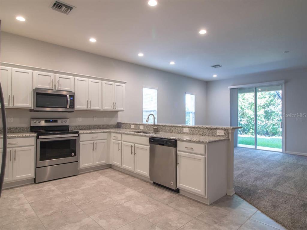A kitchen with white cabinets, stainless steel appliances, granite countertops, and tile flooring — 1097 GRANTHAM DRIVE, SARASOTA, FL
