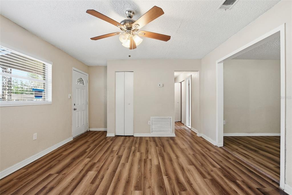 A living room with wood-look flooring, a ceiling fan, and a white front door — 4132 WESTGATE ROAD, ORLANDO, FL