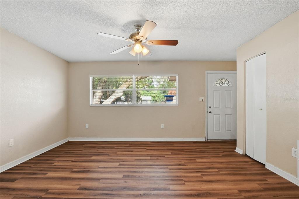 An empty room features light-colored walls, wood-look flooring, a ceiling fan, and a white door — 4132 WESTGATE ROAD, ORLANDO, FL