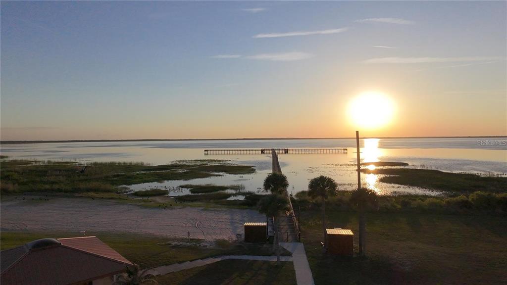 An aerial view of a long wooden pier extending into a lake at sunset — OLEANDER DRIVE, INDIAN LAKE ESTATES, FL