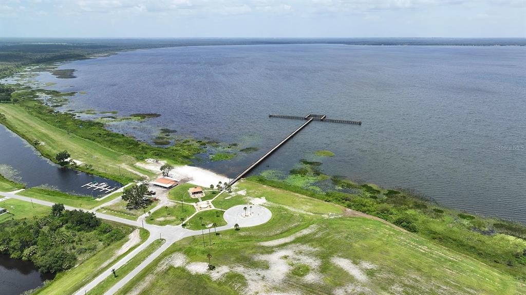 An aerial view shows a long wooden pier extending into a large lake — OLEANDER DRIVE, INDIAN LAKE ESTATES, FL