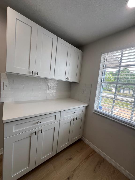 A kitchen area features white shaker cabinets, a white countertop, and a subway tile backsplash — 4223 SHELDON PLACE UNIT 23, NEW PORT RICHEY, FL