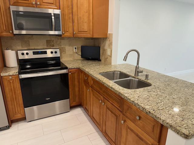 A kitchen features wood cabinets, granite countertops, stainless steel appliances, and a double-basin sink — 7605 NW 5th Court NW # 208, Margate FL 33063, MARGATE, FL