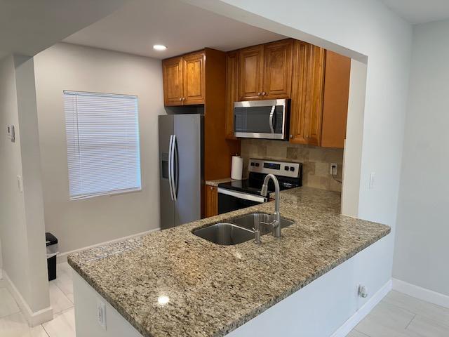A kitchen features wood cabinets, granite countertops, stainless steel appliances, and a breakfast bar — 7605 NW 5th Court NW # 208, Margate FL 33063, MARGATE, FL