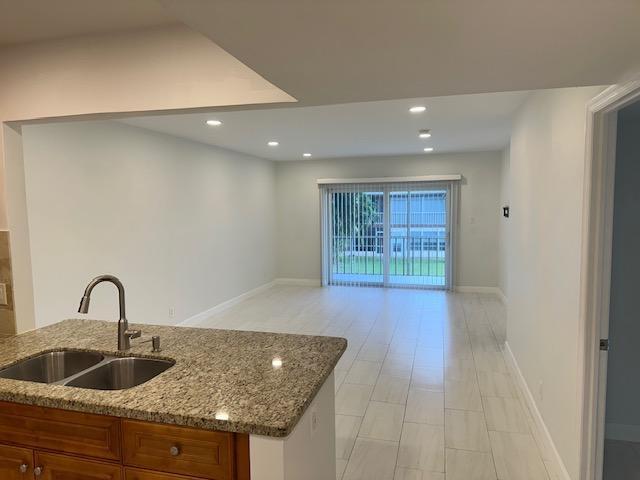 A kitchen with granite countertops overlooks an open living area with tile flooring and balcony — 7605 NW 5th Court NW # 208, Margate FL 33063, MARGATE, FL