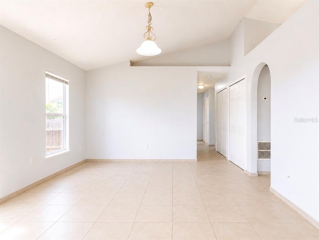 An empty room with beige tile flooring, white walls, a vaulted ceiling, and a pendant light — 508 POINTE ALLYSON WAY, ORLANDO, FL