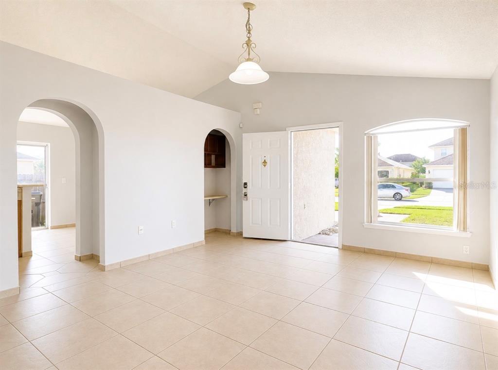 A bright, tiled living area features an arched entryway, a built-in desk, and a front door — 508 POINTE ALLYSON WAY, ORLANDO, FL