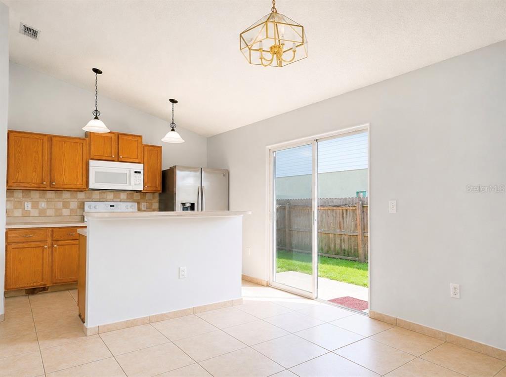 A kitchen with wood cabinets and a breakfast bar opens to a dining area — 508 POINTE ALLYSON WAY, ORLANDO, FL