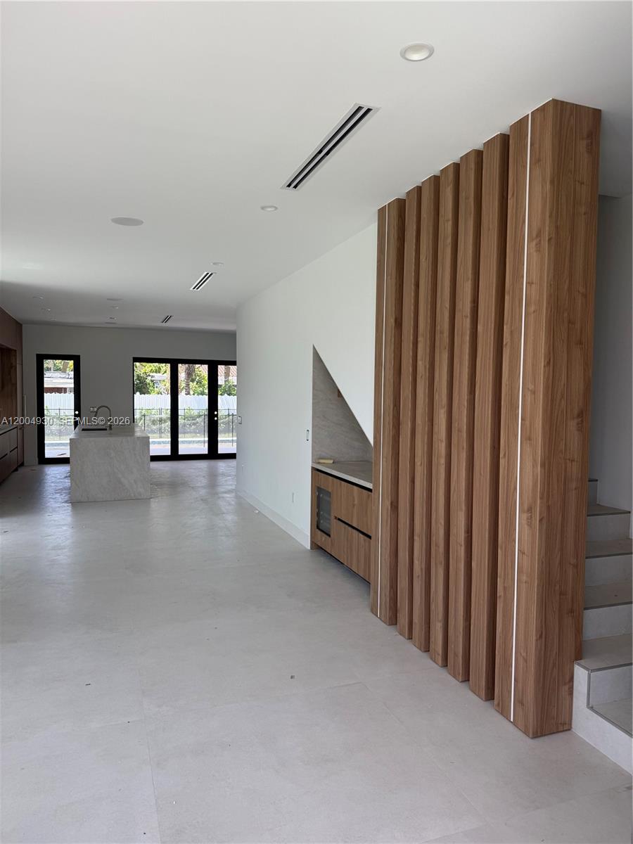 A modern interior features a kitchen, a wood-slatted staircase partition, and light-colored tile flooring — 6449 SW 28th St, Miami FL 33155, MIAMI, FL