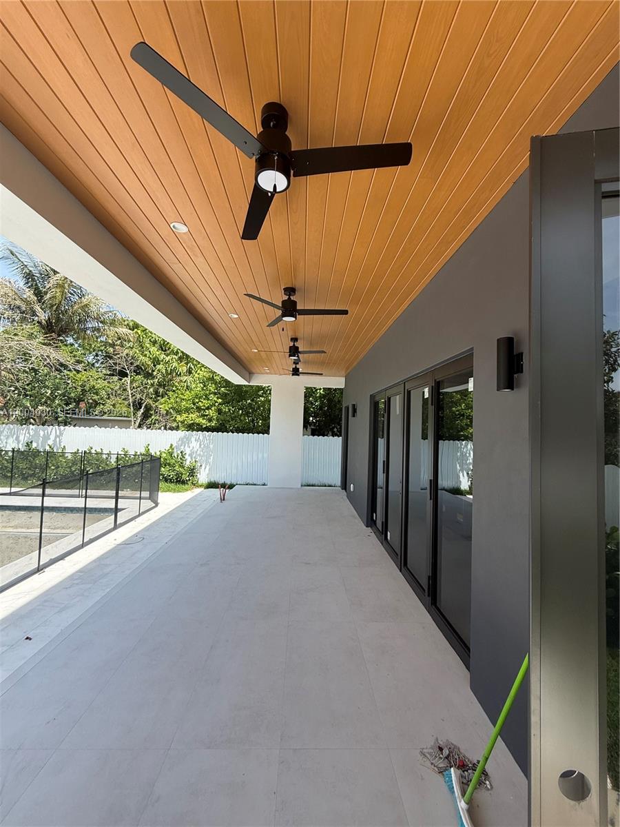 A covered patio features a wood-paneled ceiling with three ceiling fans and large glass doors — 6449 SW 28th St, Miami FL 33155, MIAMI, FL