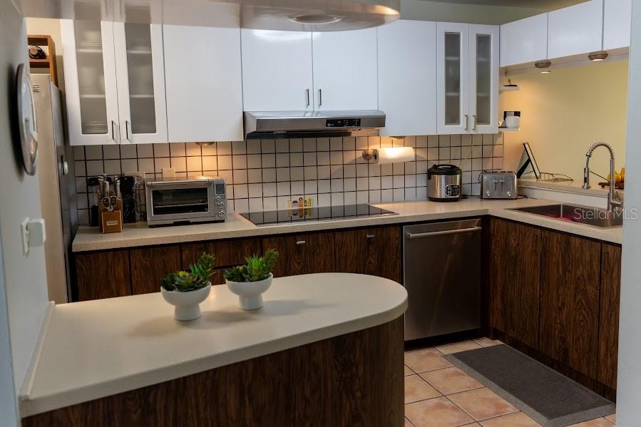 A kitchen features white upper cabinets, wood-grain lower cabinets, a tiled backsplash, and stainless appliances — 66 VILLAS DEL GOLF ESTE 66 Este, DORADO, PR