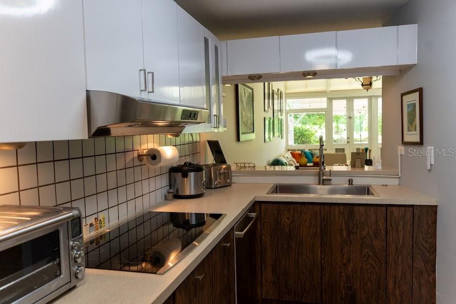 A kitchen features white upper cabinets, wood-grain lower cabinets, a stainless steel sink, and appliances — 66 VILLAS DEL GOLF ESTE 66 Este, DORADO, PR
