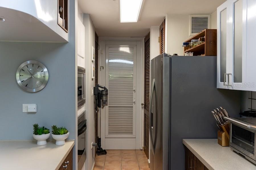 A kitchen features a stainless steel refrigerator, white cabinetry, a wall oven, and a glass door — 66 VILLAS DEL GOLF ESTE 66 Este, DORADO, PR