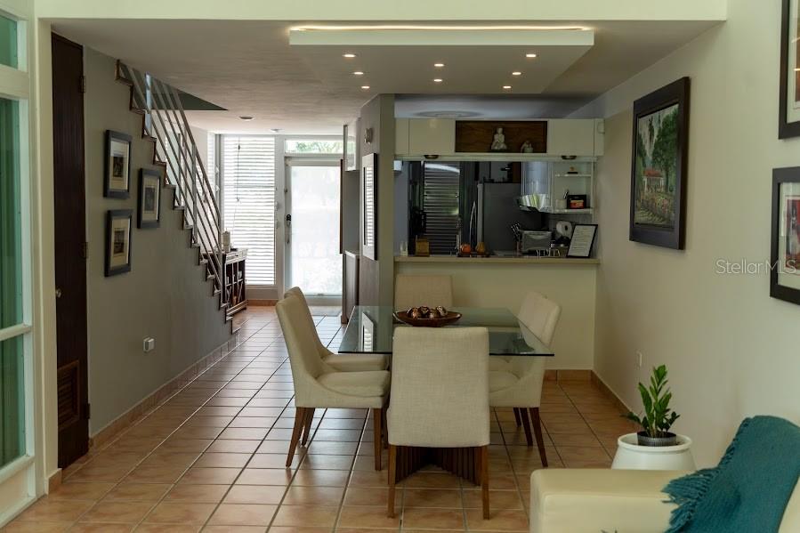 A dining area with a glass table and chairs sits next to a staircase and kitchen — 66 VILLAS DEL GOLF ESTE 66 Este, DORADO, PR