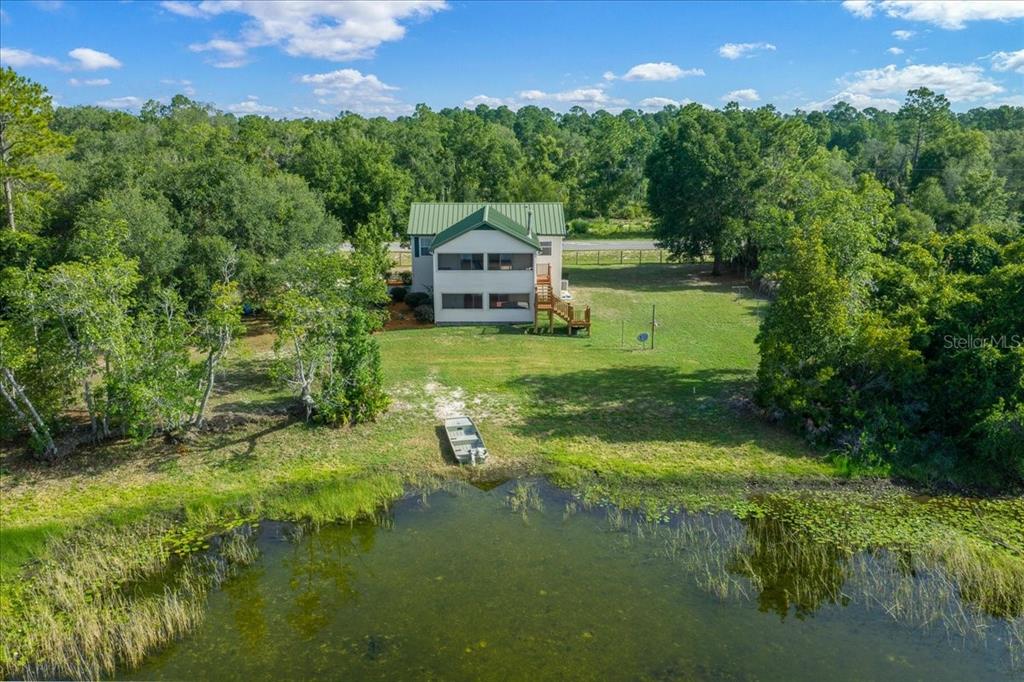 An aerial view shows a house with a green roof situated on a grassy lot — 206 MALAUKA RADIAL, OCKLAWAHA, FL