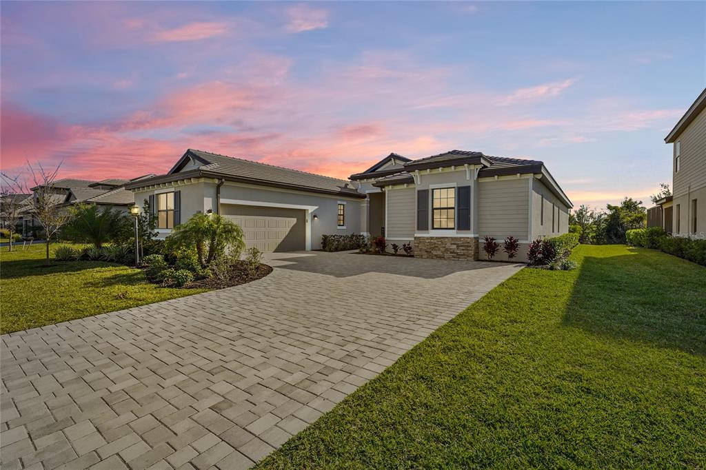 A single-story house with a paved driveway, a two-car garage, and stone exterior accents — 15330 GOLDEN BEAM PLACE, BRADENTON, FL