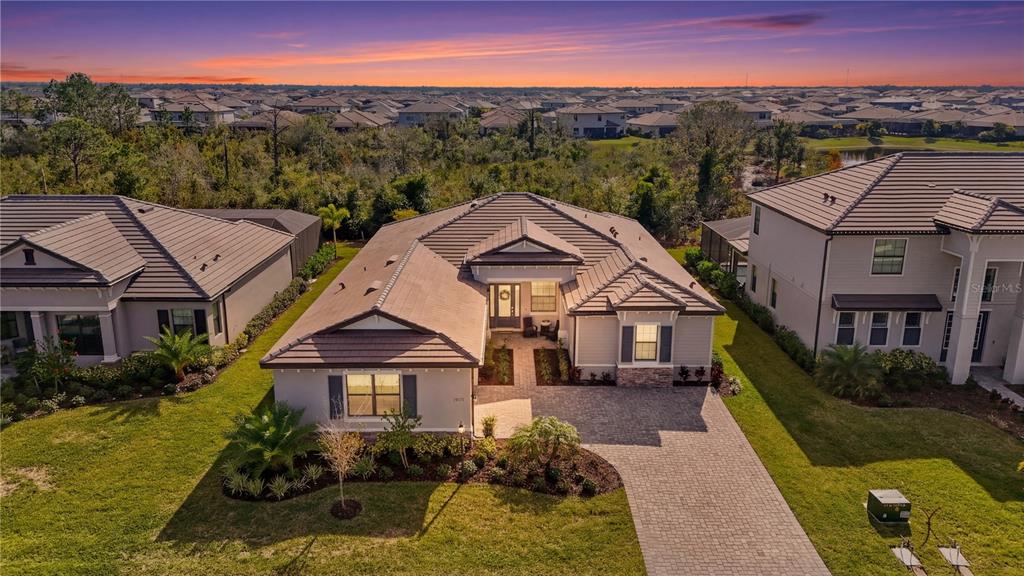An aerial view of a single-story suburban house with a tiled roof and paver driveway — 15330 GOLDEN BEAM PLACE, BRADENTON, FL