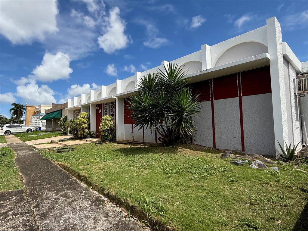 A low-rise building with a white facade, arched roofline, and a prominent palm tree — T-10 MCKINLEY, GUAYNABO, PR