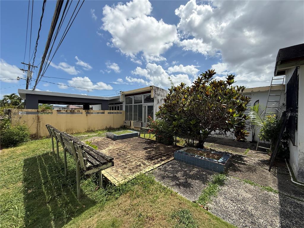 An outdoor patio features a tiled area, a large tree, and a wooden bench — T-10 MCKINLEY, GUAYNABO, PR