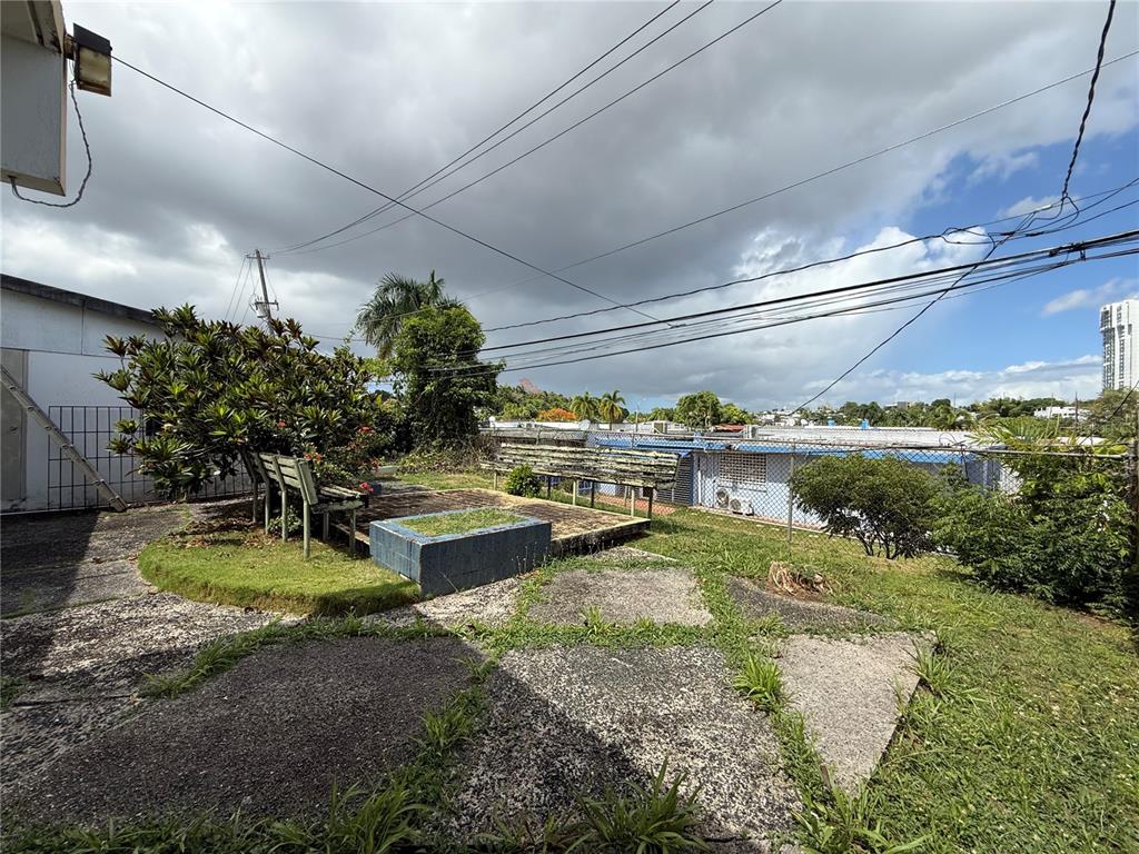 A backyard features a concrete patio, a small raised garden bed, and wooden benches — T-10 MCKINLEY, GUAYNABO, PR