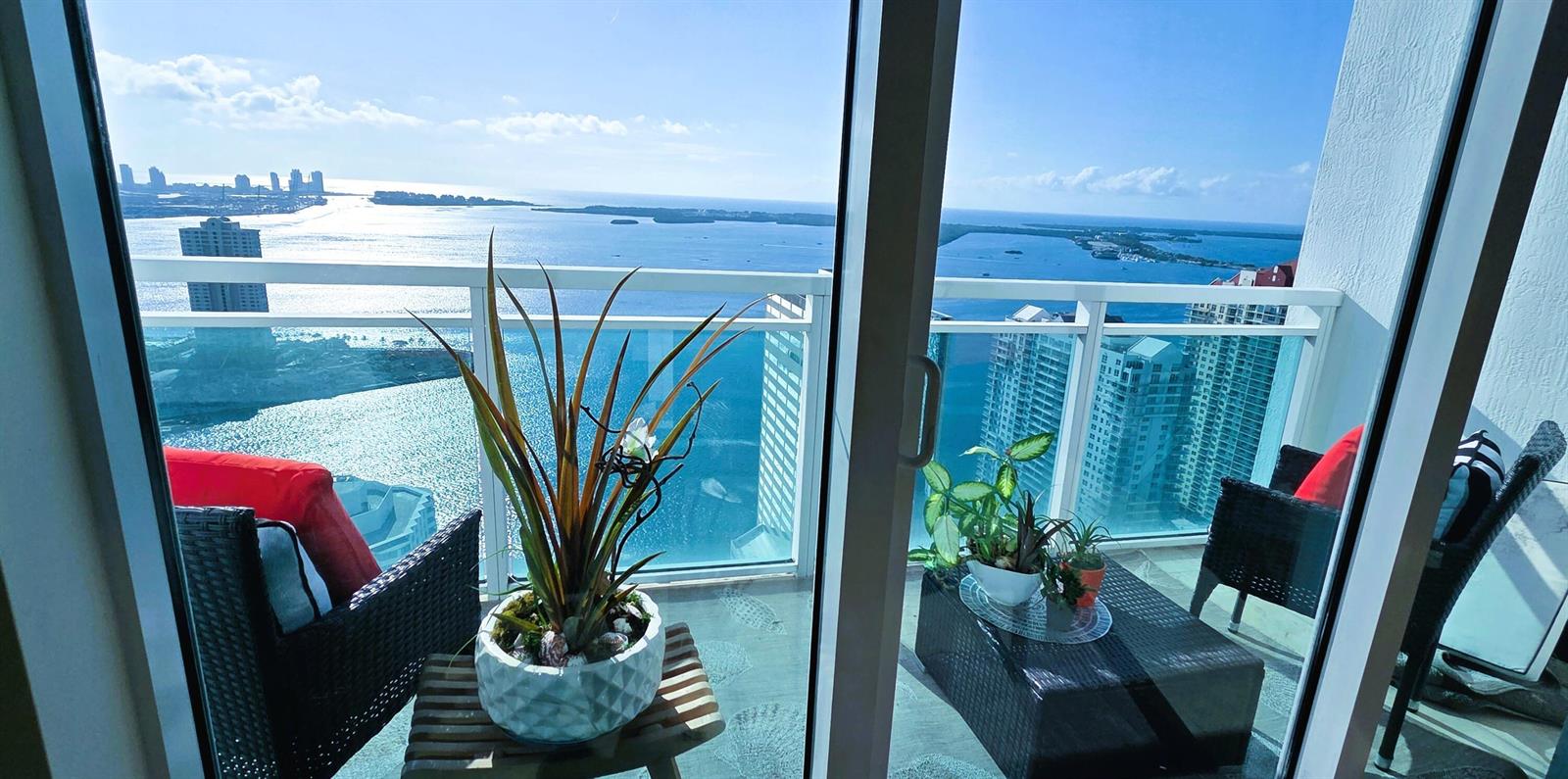 A balcony with patio furniture and potted plants overlooks a bay and city skyline — 951 Brickell Avenue # 4308, Miami FL 33131, MIAMI, FL