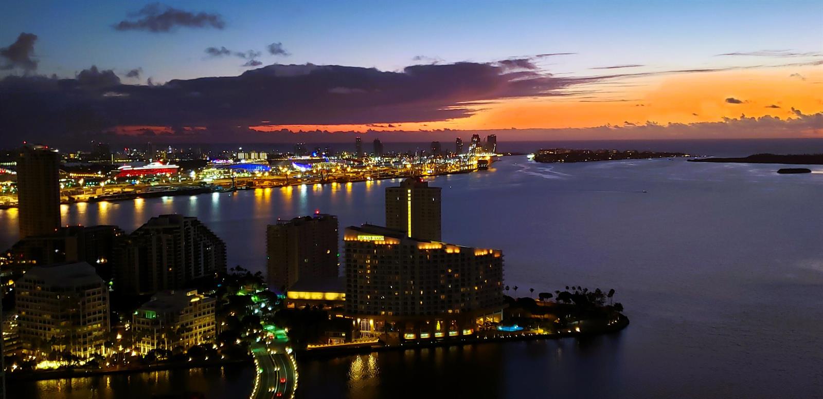 An aerial view of a coastal city skyline at sunset with illuminated buildings and water — 951 Brickell Avenue # 4308, Miami FL 33131, MIAMI, FL