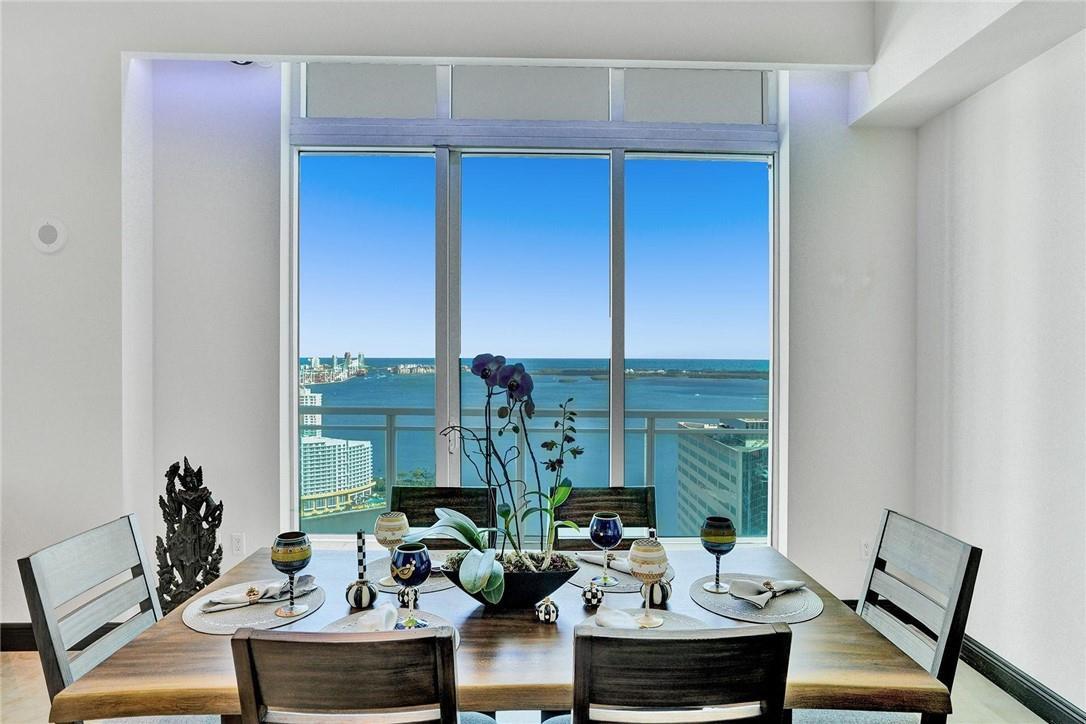 A dining room features a wooden table, six chairs, and floor-to-ceiling windows overlooking the ocean — 951 Brickell Avenue # 4308, Miami FL 33131, MIAMI, FL