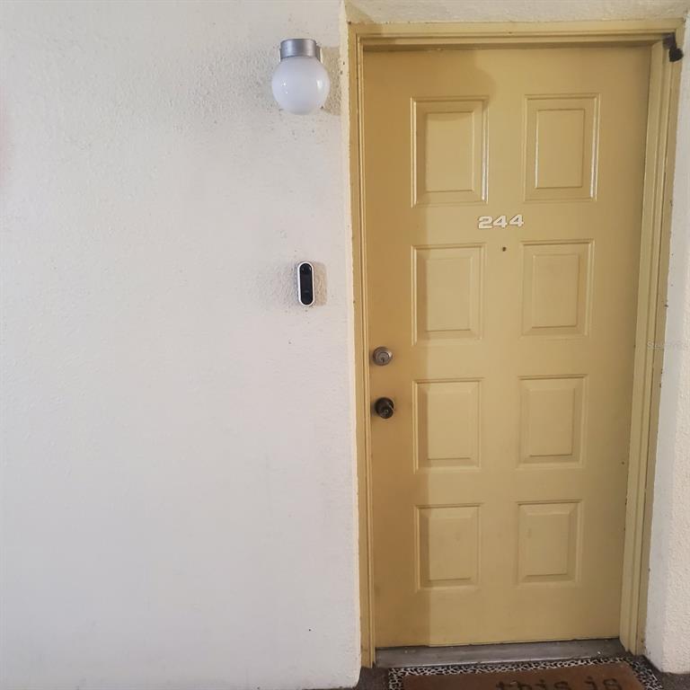 A yellow exterior door numbered 244 features a doorbell camera and a wall-mounted light fixture — 3525 E FORT KING STREET UNIT 244, OCALA, FL