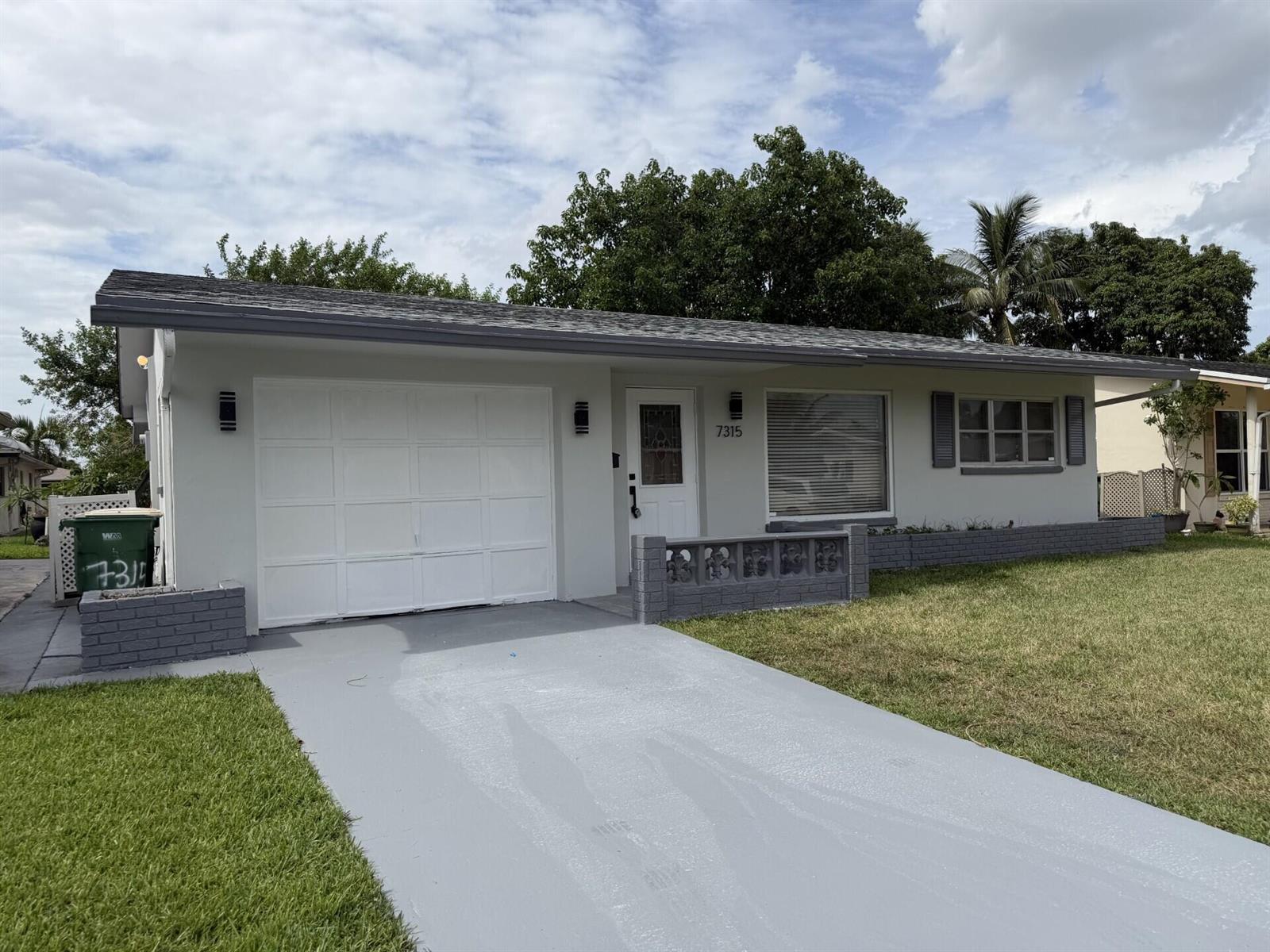 A single-story house with a white garage, gray trim, and a small front patio area — 7315 NW 57th Place, Tamarac FL 33321, TAMARAC, FL