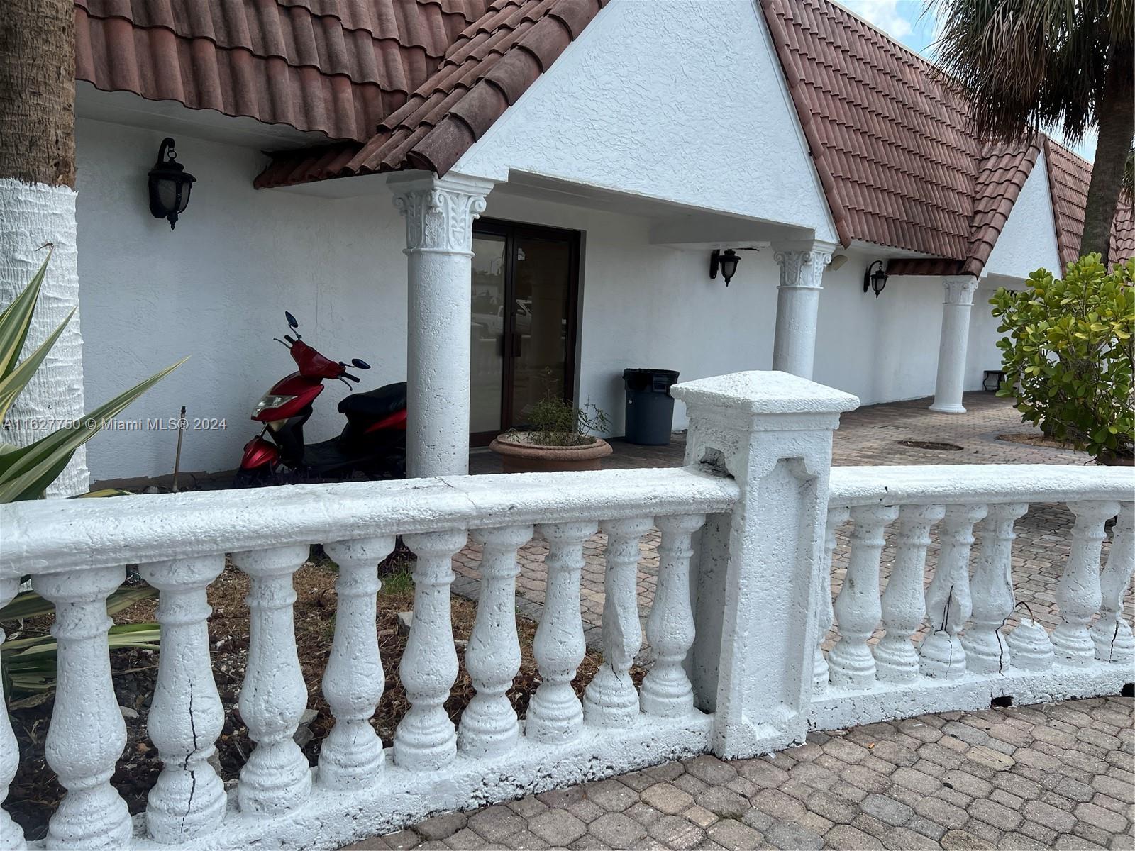 A white building exterior features a tiled roof, classical columns, and a decorative balustrade — 16805 NW 12th Ave, Miami Gardens FL 33169, MIAMI GARDENS, FL