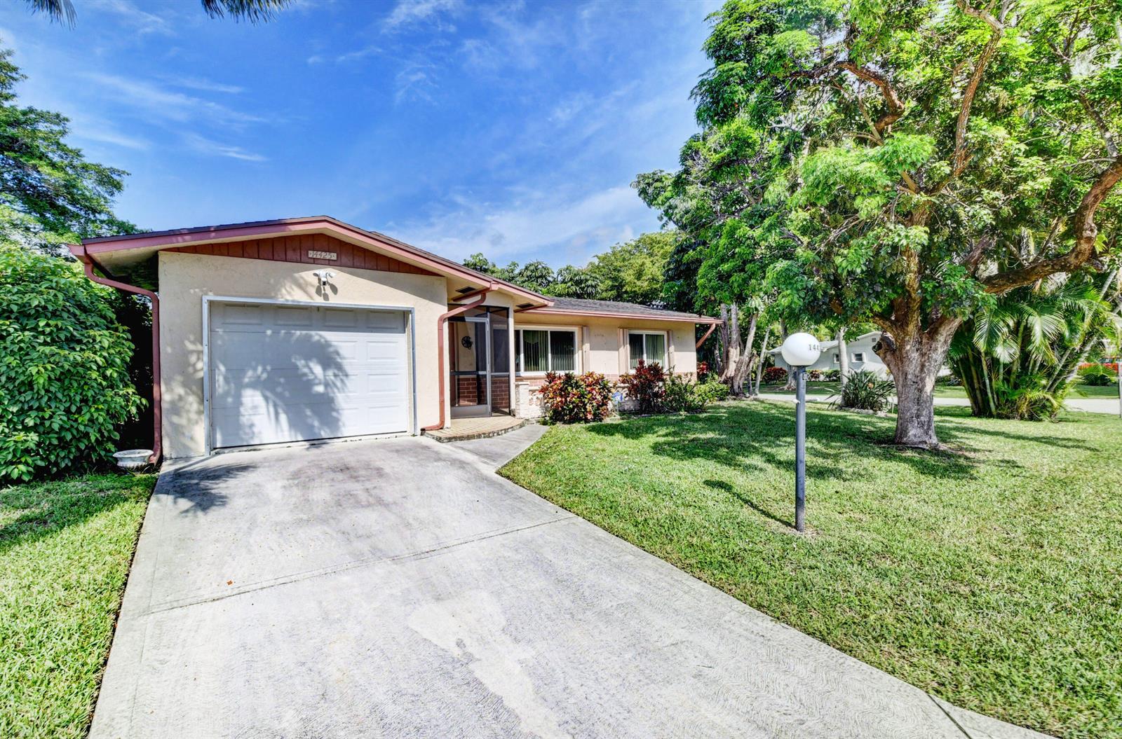 A single-story house with a white garage, beige exterior, and a large tree in front — 14425 Amapola Way, Delray Beach FL 33484, DELRAY BEACH, FL