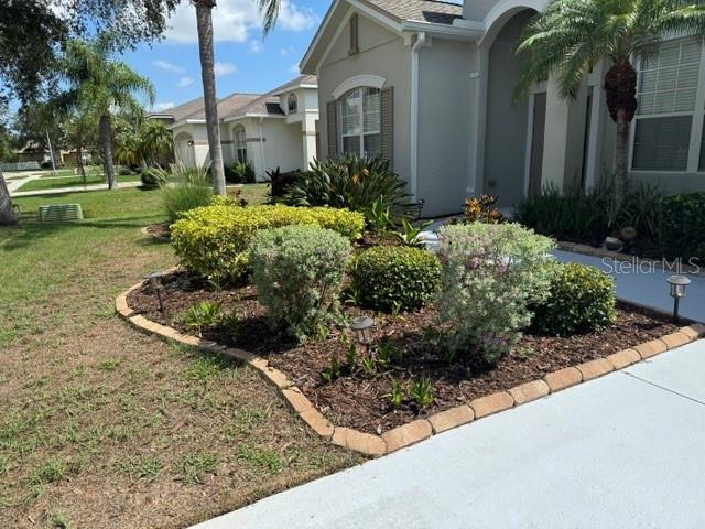 A landscaped garden bed with shrubs and solar lights sits in front of a house — 6145 E 41 STREET, BRADENTON, FL