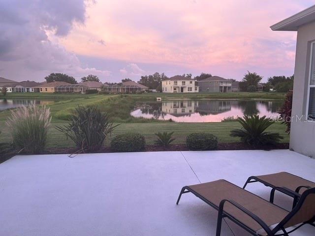 A concrete patio overlooks a grassy lawn, a small pond, and several suburban houses — 6145 E 41 STREET, BRADENTON, FL
