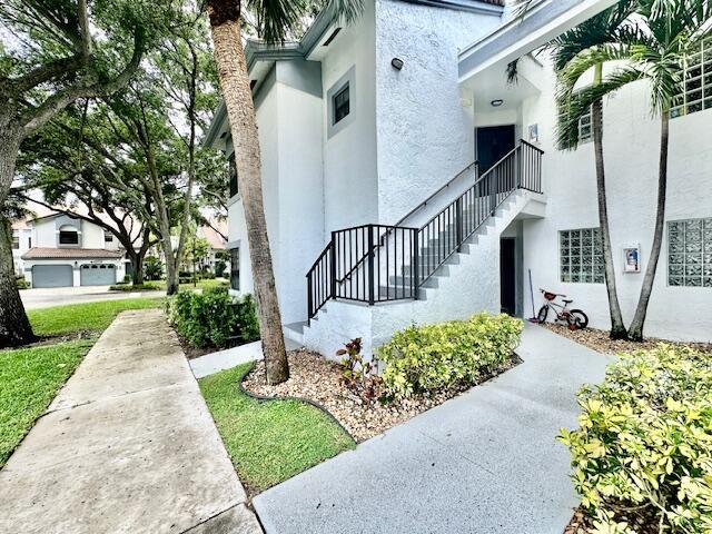 An exterior view of a white multi-story building with a staircase and a small bicycle — 5430 Venetia Court, Boynton Beach FL 33437, BOYNTON BEACH, FL