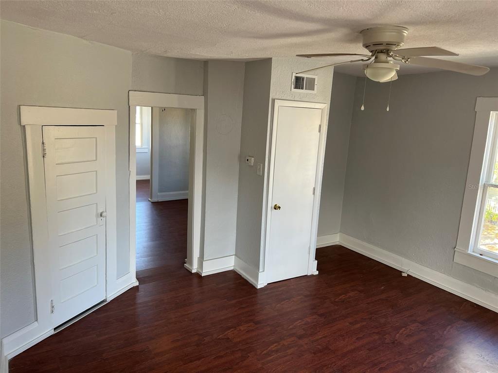 A room with gray walls, dark wood-look flooring, a ceiling fan, and two white doors — 901 PENNSYLVANIA AVENUE UNIT 4, LAKELAND, FL