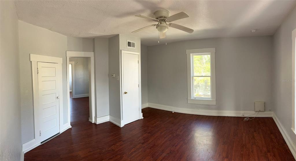 An empty room with gray walls, dark wood flooring, a ceiling fan, and two doors — 901 PENNSYLVANIA AVENUE UNIT 4, LAKELAND, FL