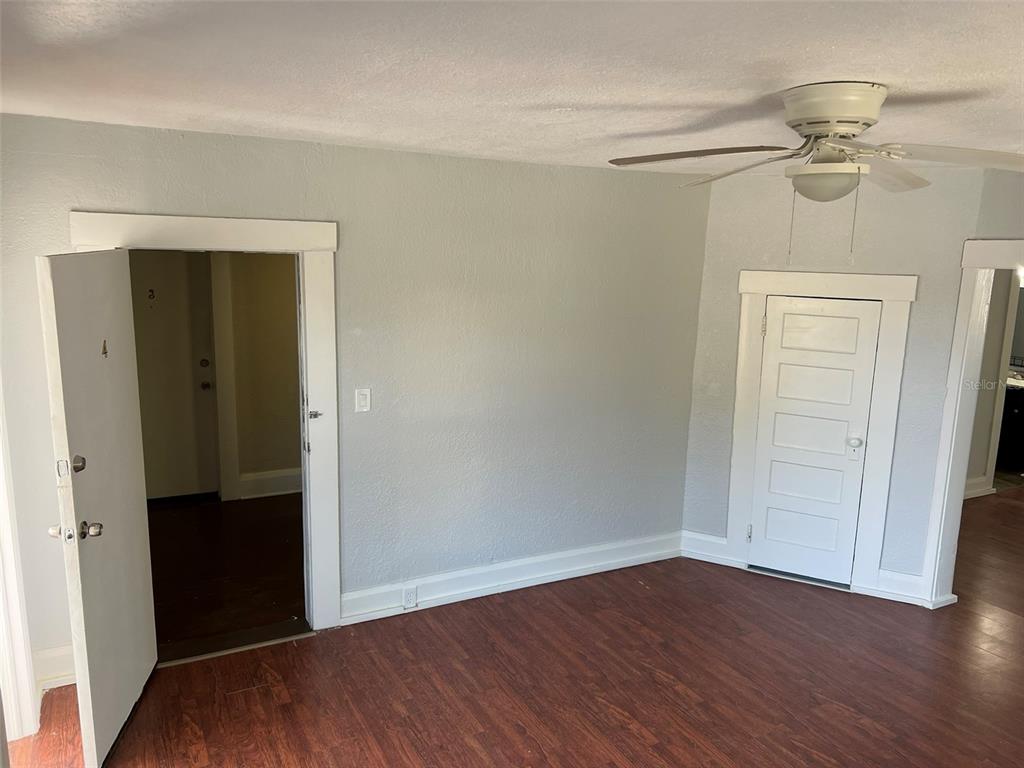 A room with gray walls, wood-look flooring, a ceiling fan, and two white doors — 901 PENNSYLVANIA AVENUE UNIT 4, LAKELAND, FL