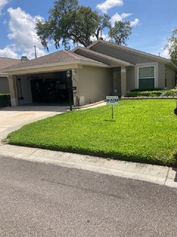 A single-story house with a tan exterior, a one-car garage, and a front lawn — 10007 BROOKDALE DRIVE, NEW PORT RICHEY, FL