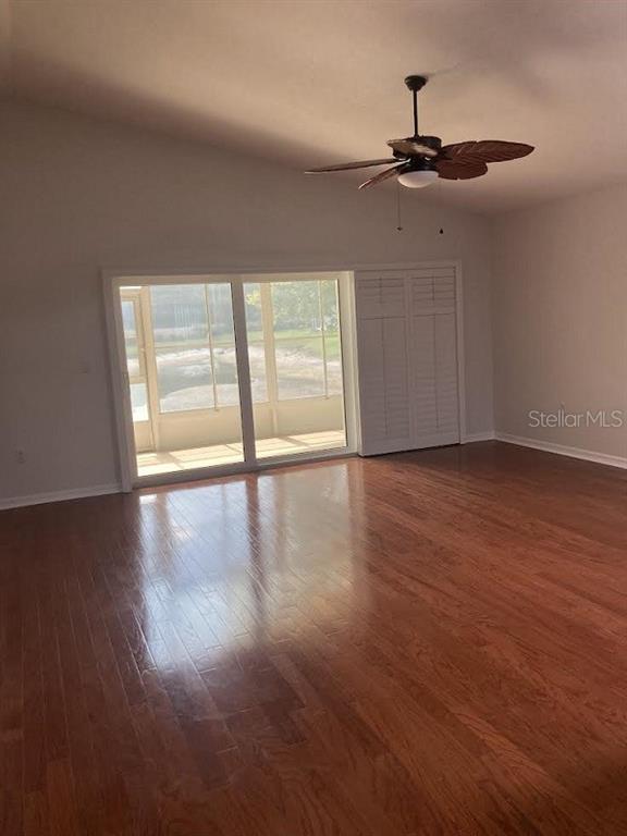 A room with hardwood floors, a ceiling fan, and sliding glass doors leading to a lanai — 10007 BROOKDALE DRIVE, NEW PORT RICHEY, FL