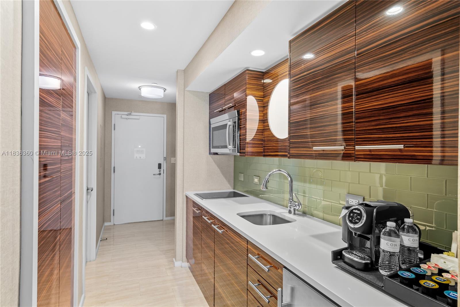 A kitchenette features wood-grain cabinets, a white countertop, a green tile backsplash, and stainless appliances — 551 N Fort Lauderdale Beach Blvd # R1909, Fort Lauderdale FL 33304, FORT LAUDERDALE, FL