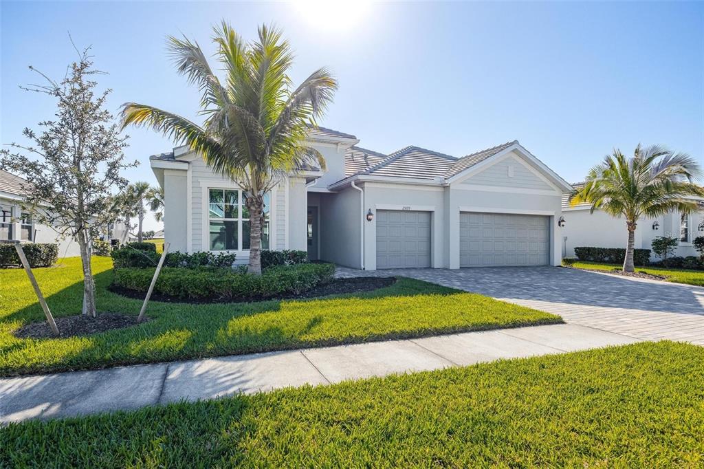 A single-story house with a paved driveway, two-car garage, and palm trees in the yard — 25199 LONGMEADOW DRIVE, PUNTA GORDA, FL