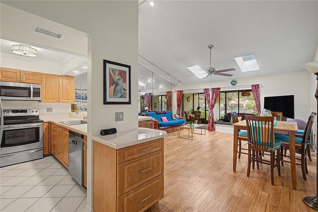 A kitchen with wood cabinets and stainless appliances opens into a living and dining area — 1206 PALM DRIVE, TARPON SPRINGS, FL