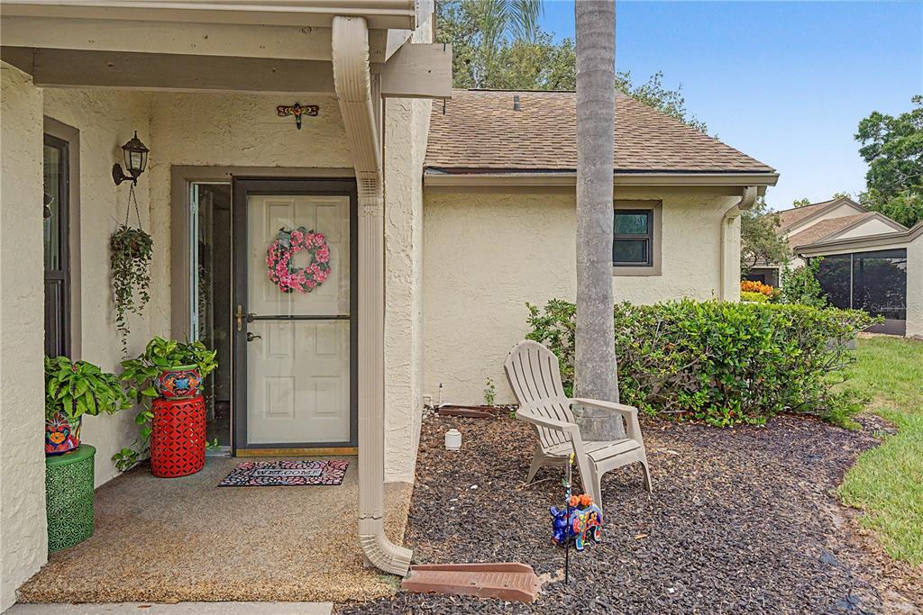 The exterior of a home features a front door, a small porch, and a lawn chair — 1206 PALM DRIVE, TARPON SPRINGS, FL