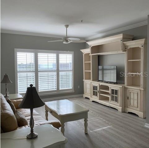 A living room features light wood flooring, a large entertainment center, and white plantation shutters — 1216 S MISSOURI AVENUE UNIT 323, CLEARWATER, FL